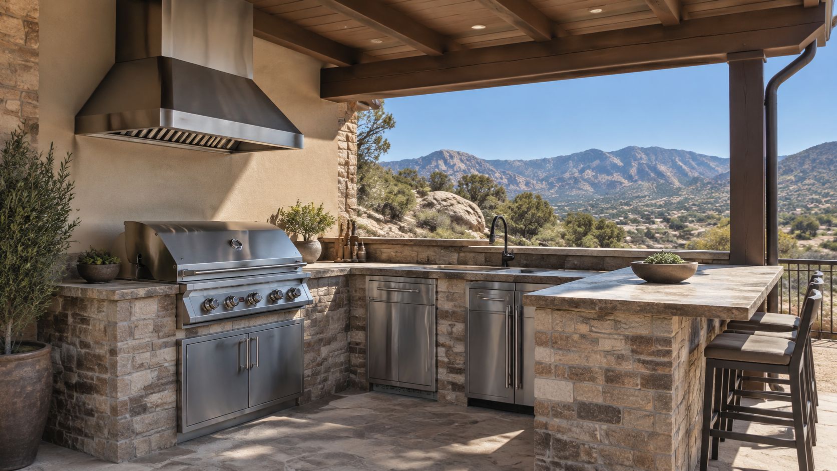 A luxurious outdoor kitchen featuring a stainless steel grill, stone masonry, and a scenic mountain view backdrop.
