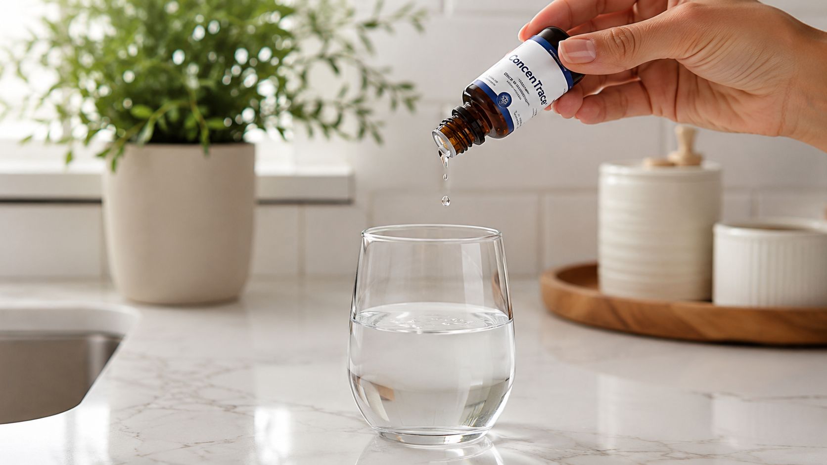 A hand carefully adds drops of ConcenTrace mineral supplement from a small glass bottle into a glass.