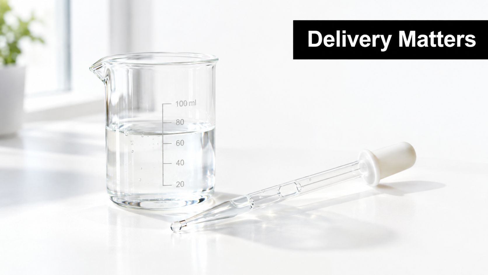 A clear glass beaker filled with liquid and a glass dropper placed on a white surface.