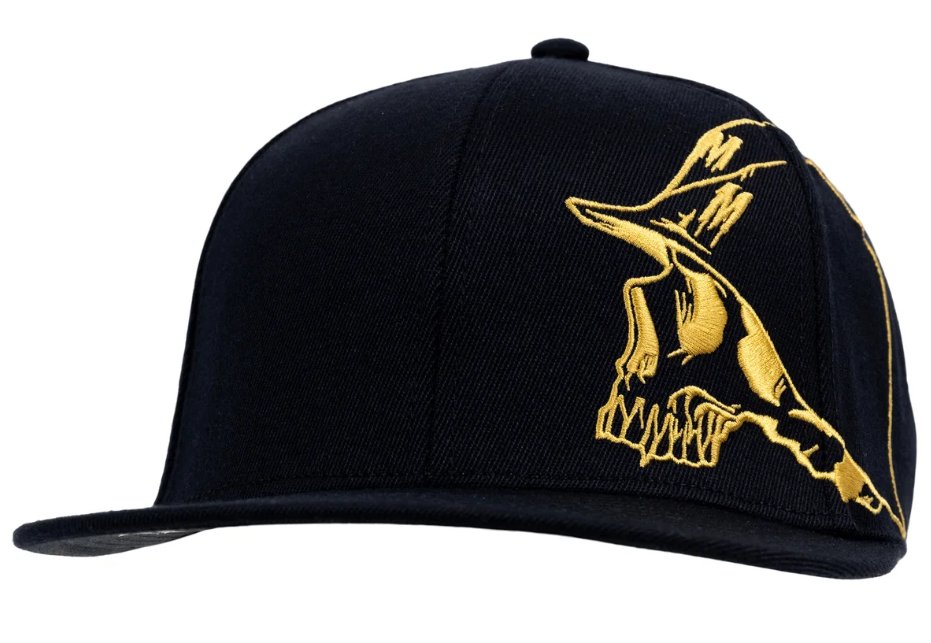A black snapback cap with a detailed gold embroidered skull wearing a top hat on the side.