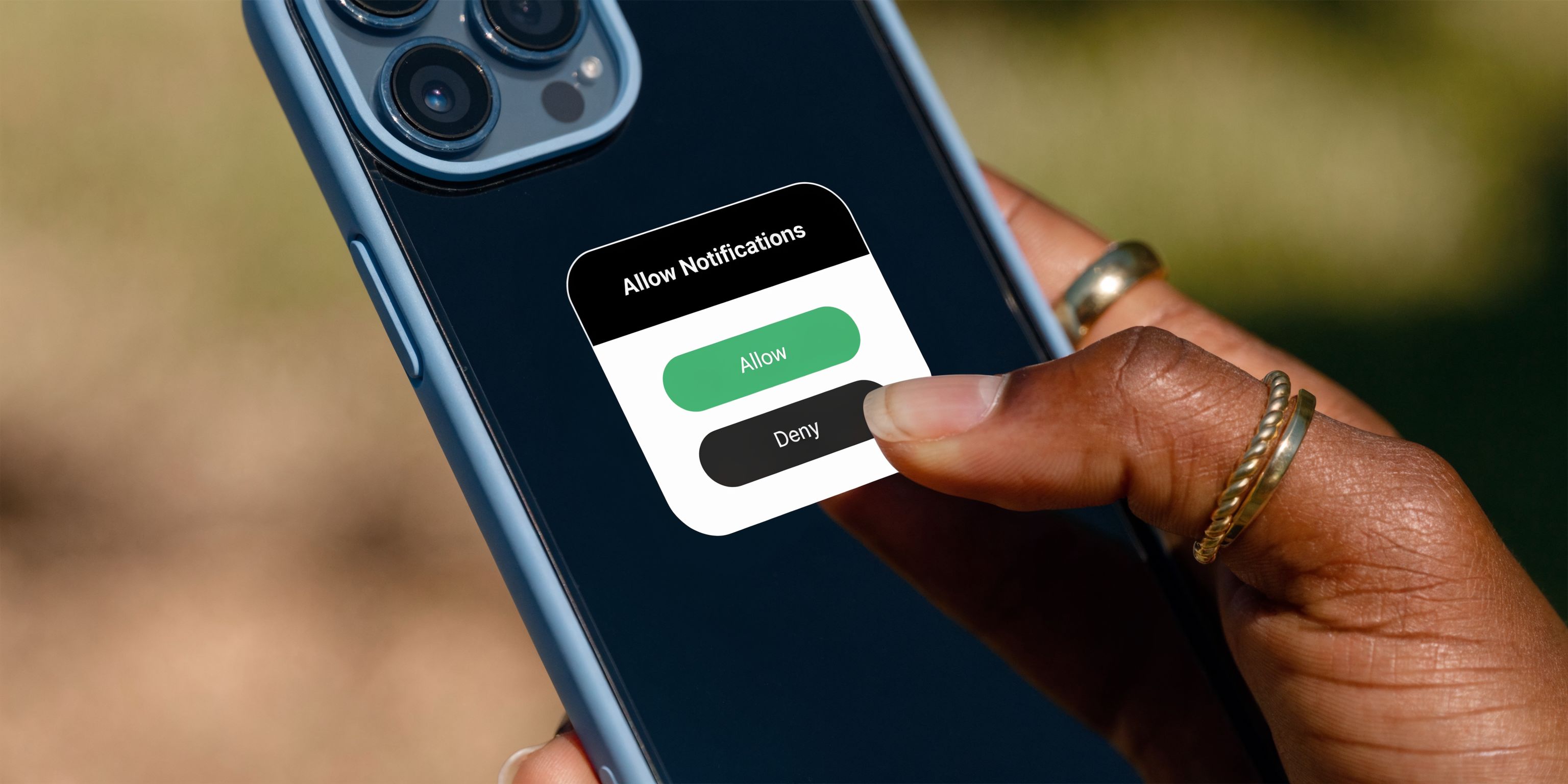 A close-up of a person's hand interacting with a permission notification prompt on a smartphone screen.