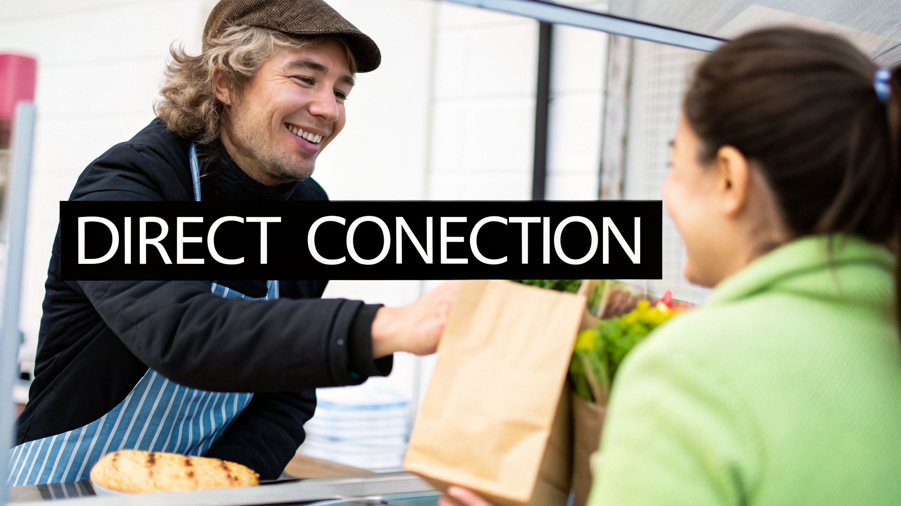 A smiling market vendor in an apron hands a paper bag to a customer, showing direct interaction.