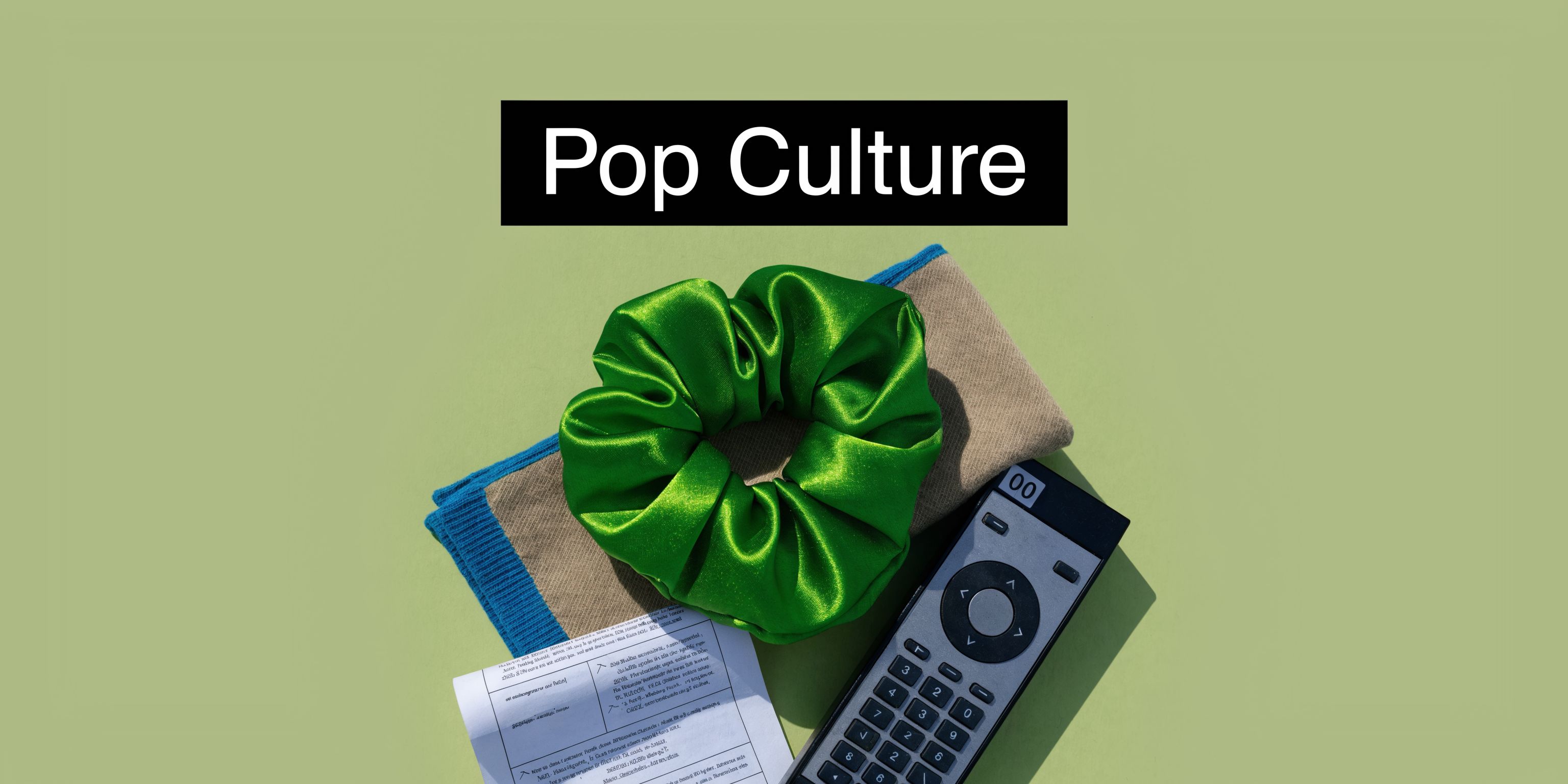 A green scrunchie, a television remote, and a document placed on a light green surface.