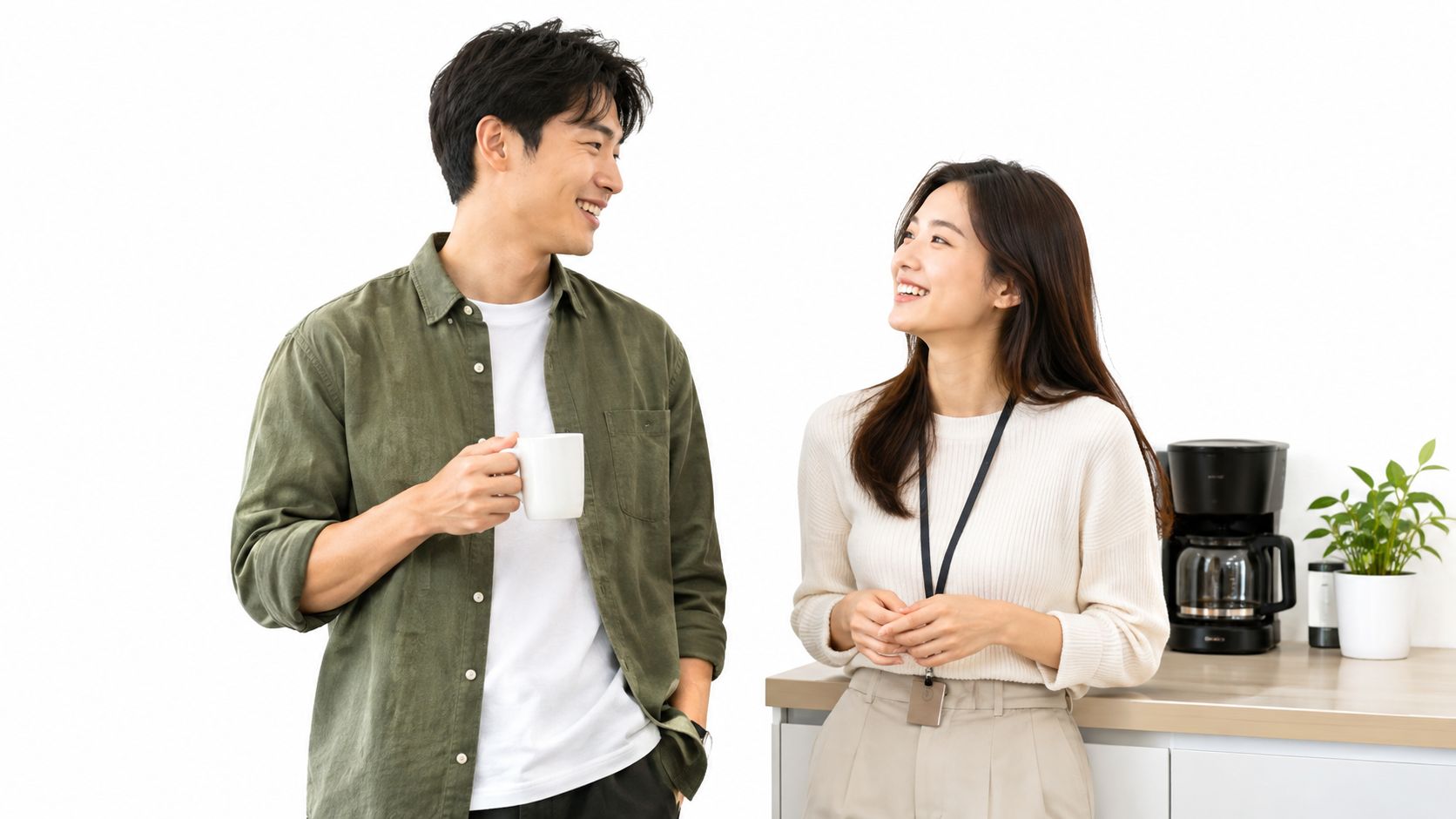 A man and a woman in office clothes smile and talk together during a coffee break.