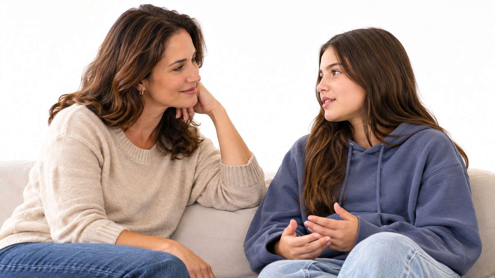 A parent and teenager sitting together at home in a calm, supportive conversation, both clearly visible in the frame, na