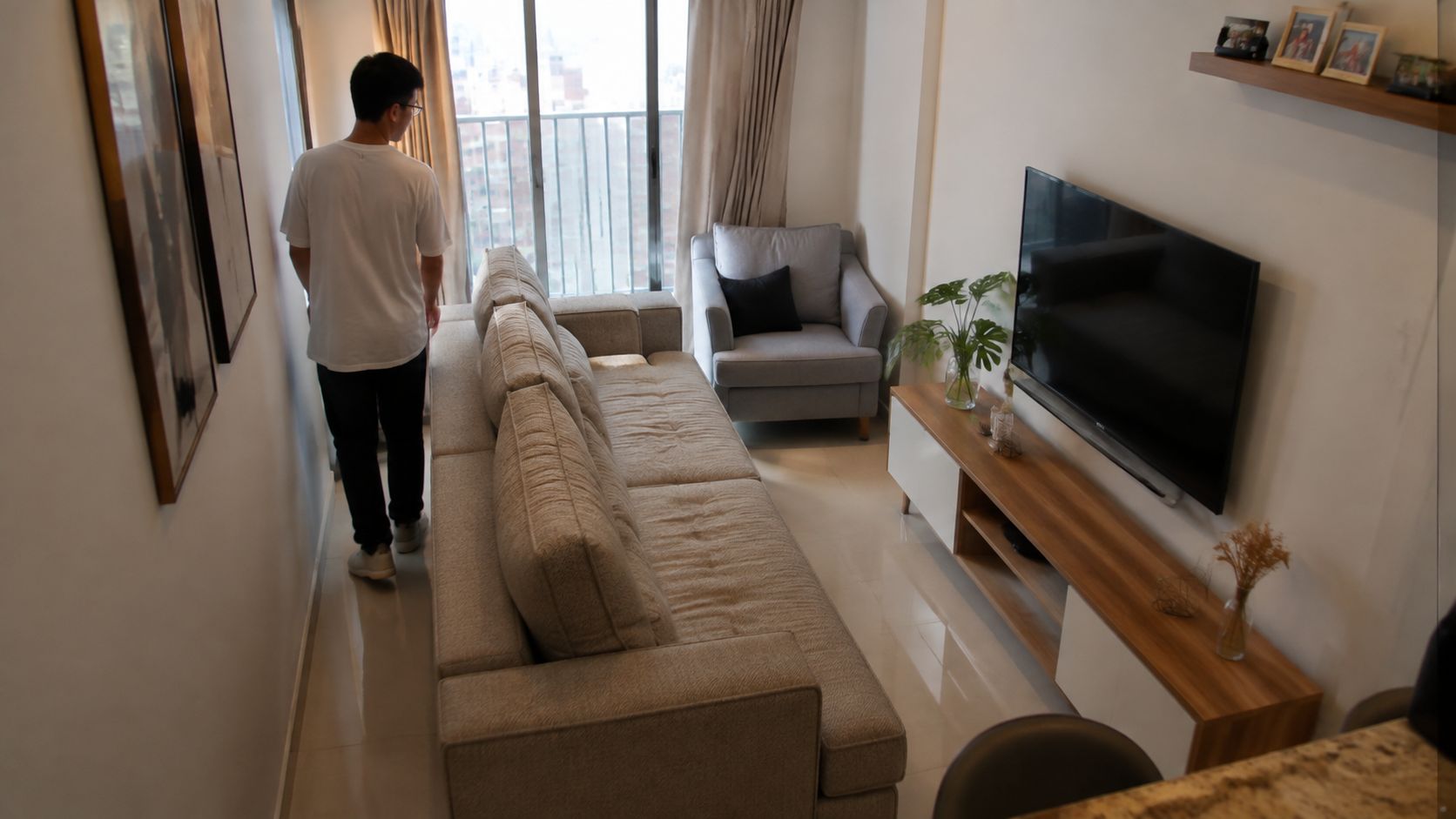 Un hombre joven de pie junto a la ventana de una sala de estar moderna y acogedora.