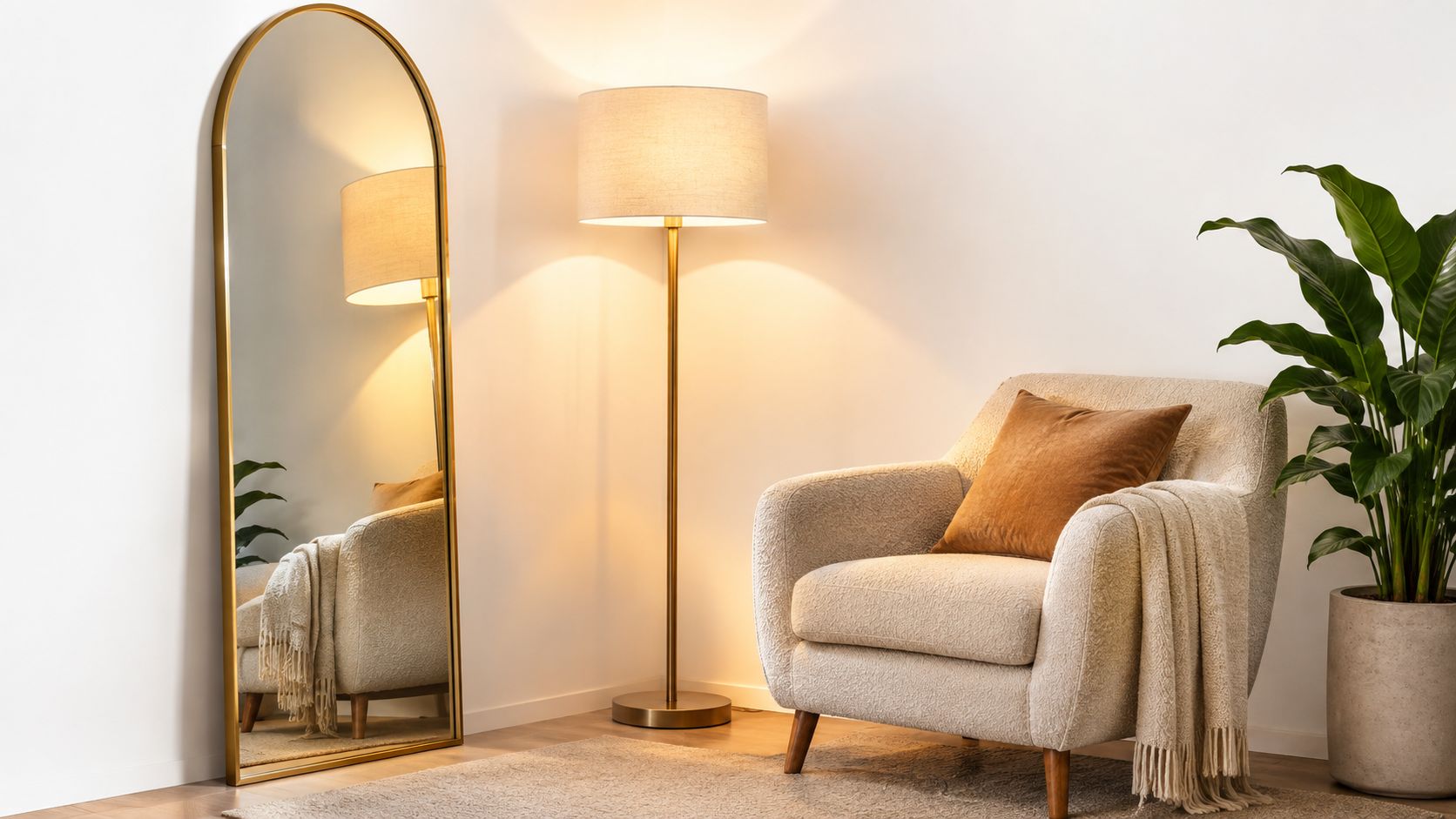 Sala moderna con espejo arqueado de marco dorado, sillón de tela clara, lámpara de pie y planta.