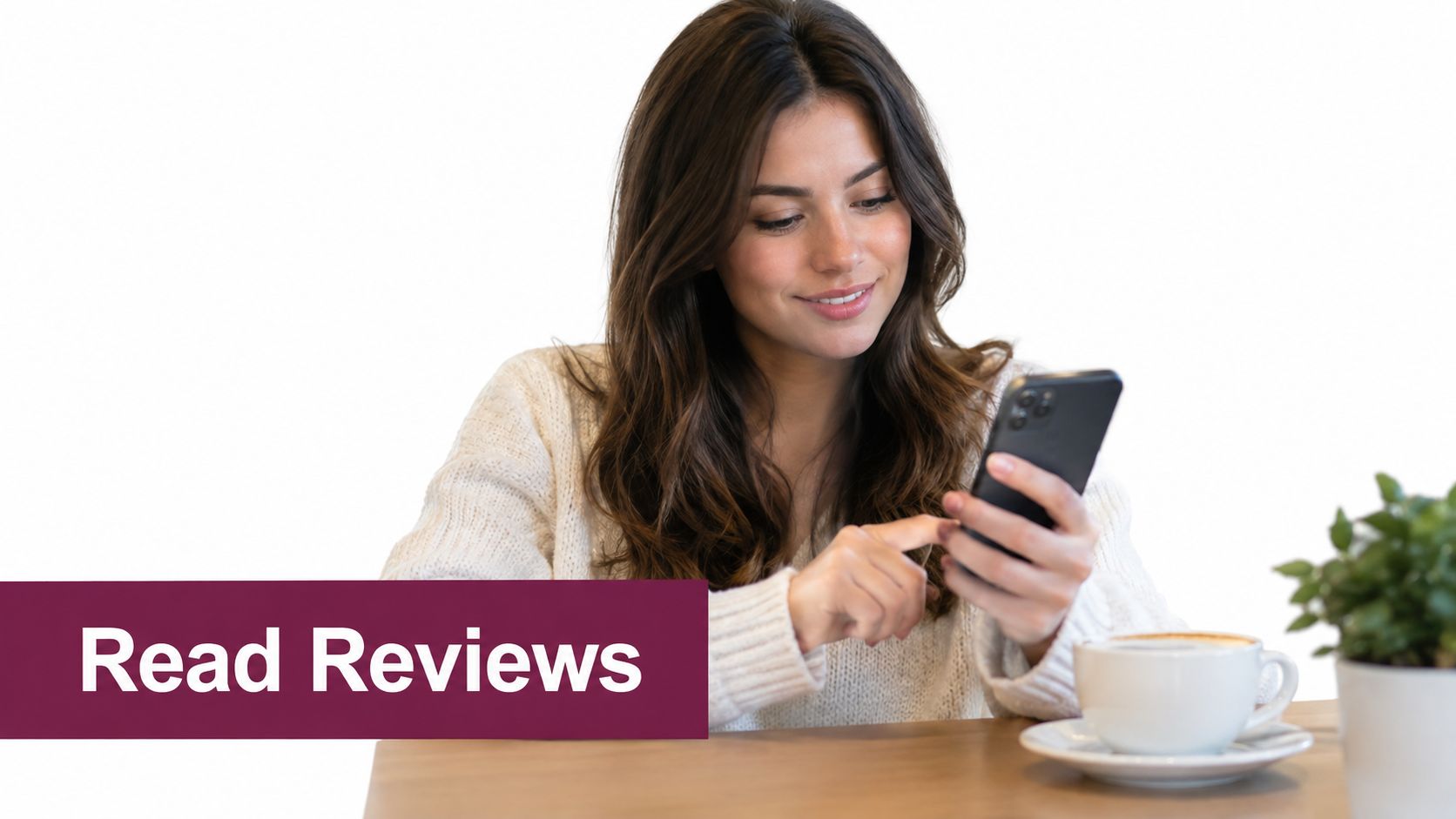 A smiling young woman sits at a table using her smartphone to read online reviews about businesses.