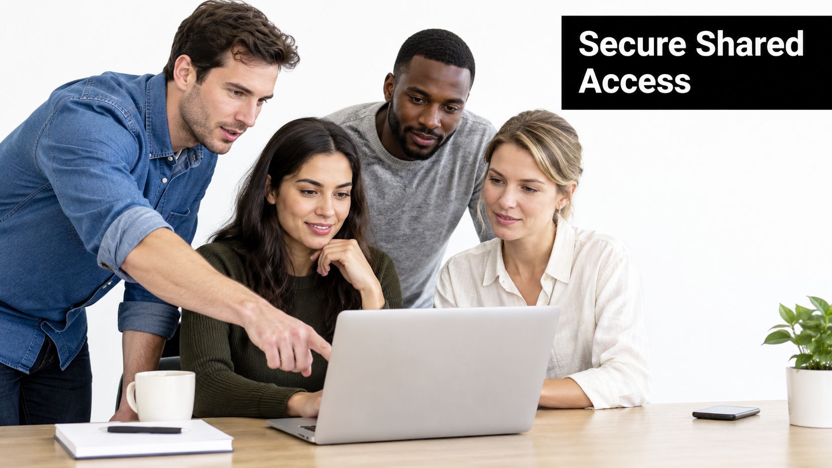 A diverse team of four professionals collaborating around a laptop on a wooden office desk.