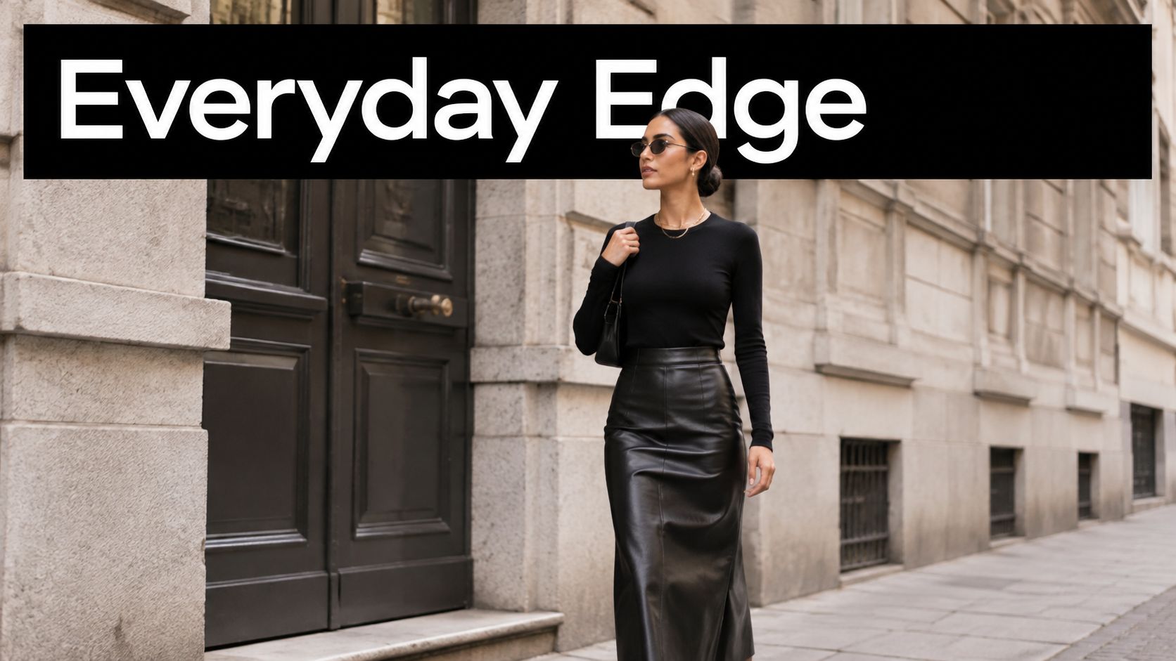 A stylish woman wearing a long leather skirt and black long-sleeve top walking down the street.