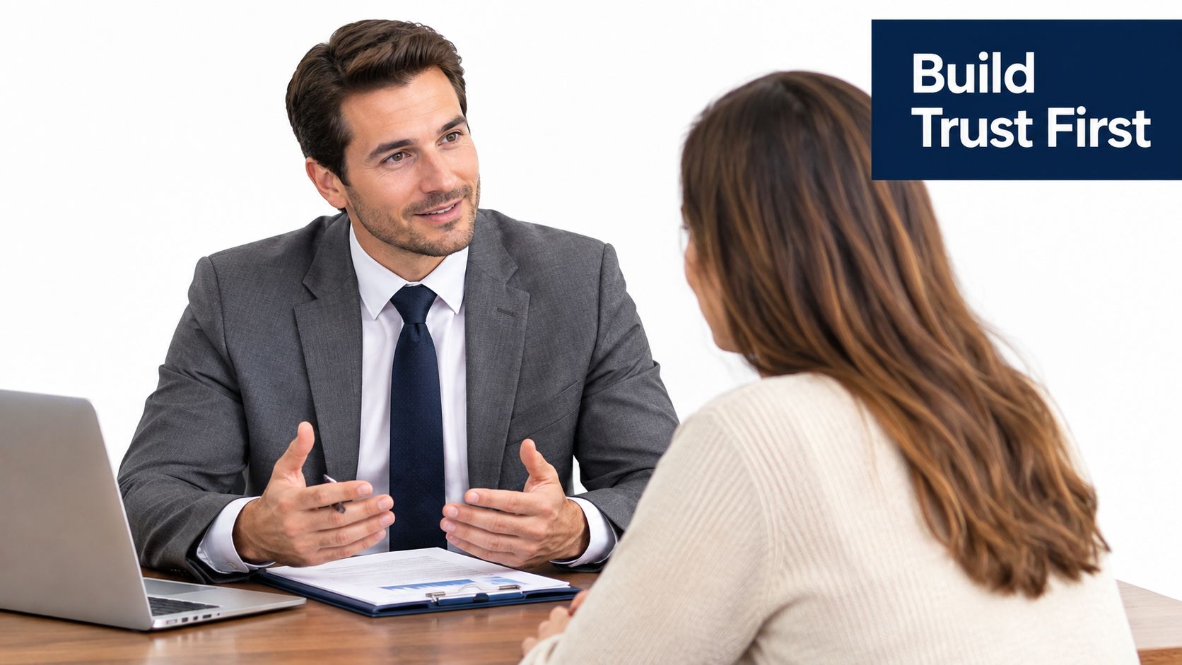 A professional financial advisor in a suit gesturing during a consultation with a client at a desk.