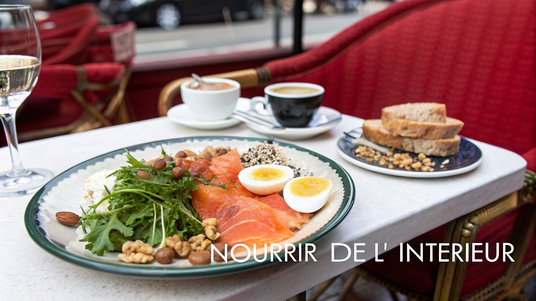 Table de café avec un plat de saumon, œufs, roquette, noix et vin blanc, plus café et pain.