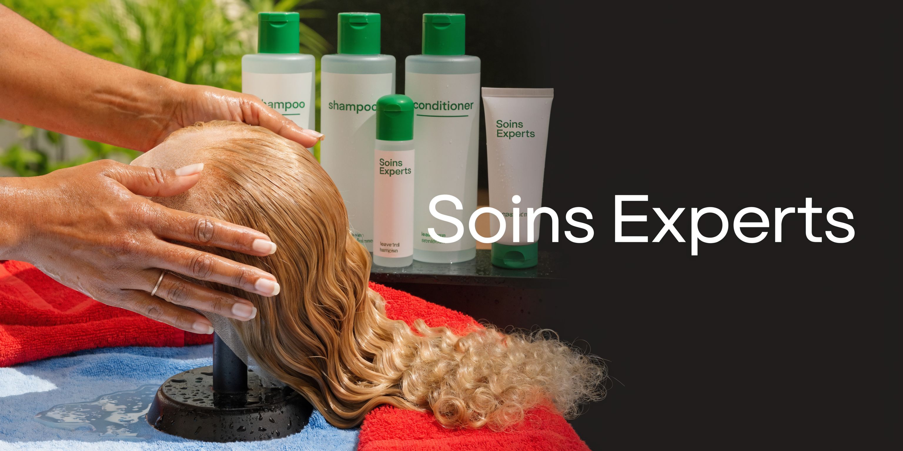 Une coiffeuse lavant délicatement une perruque blonde sur un support avec des produits de soins capillaires professionnels.