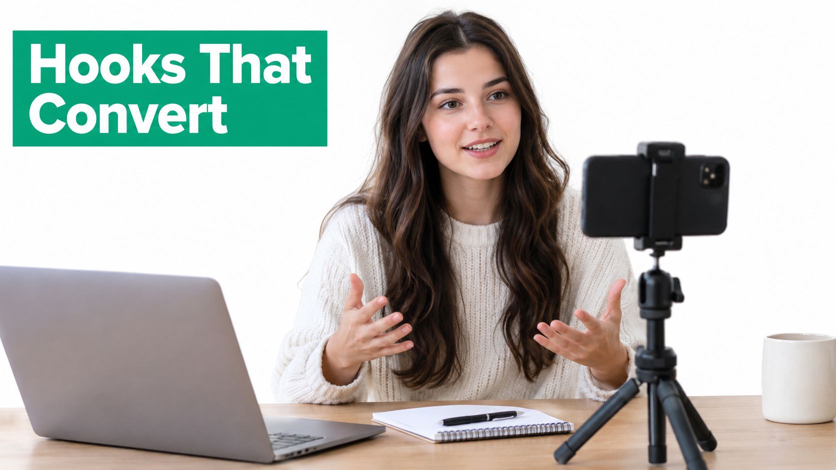 A woman creating content for social media while sitting at her desk with a phone and laptop.