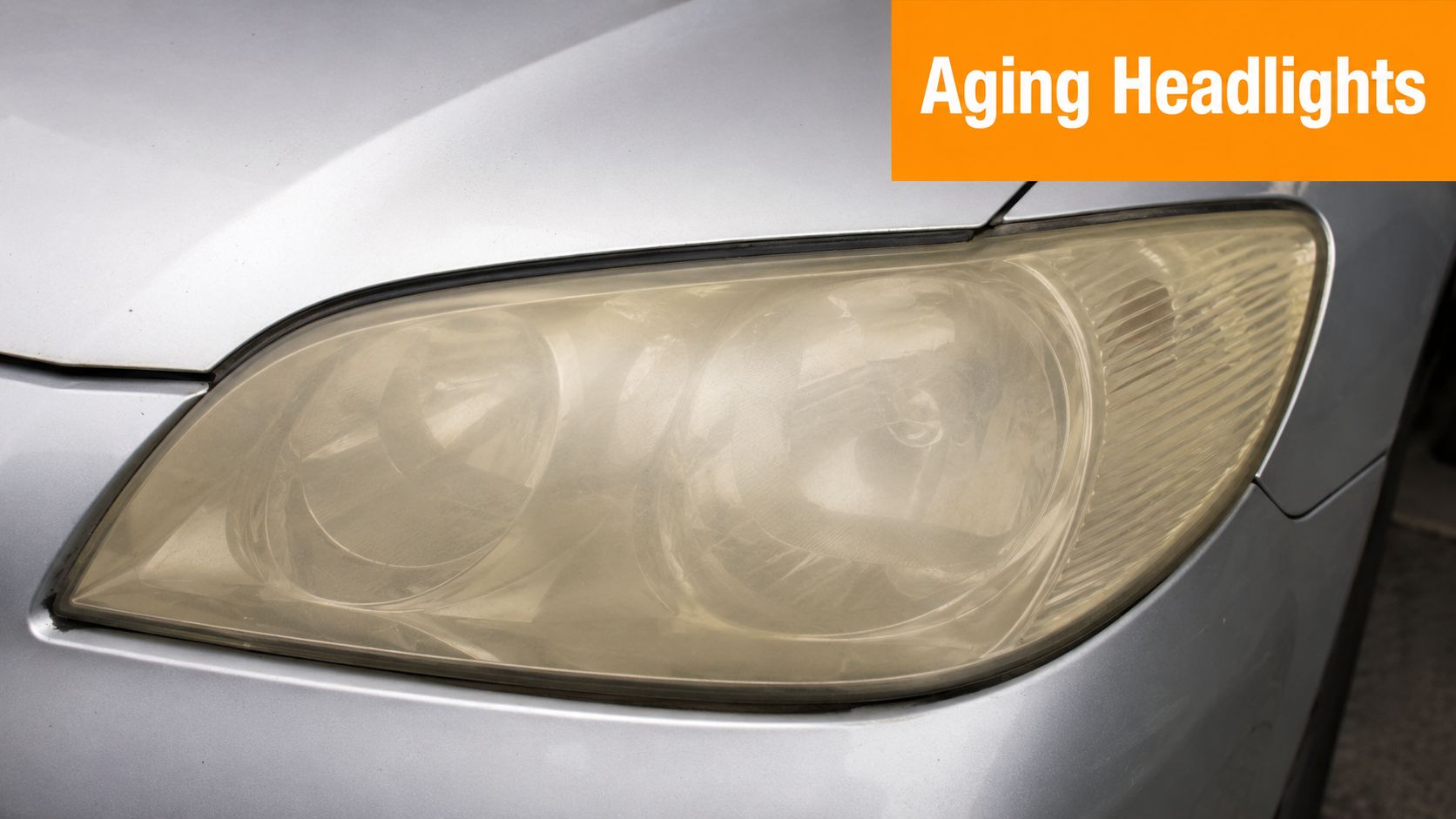 A close-up view of an oxidized and yellowed car headlight cover showing signs of aging.
