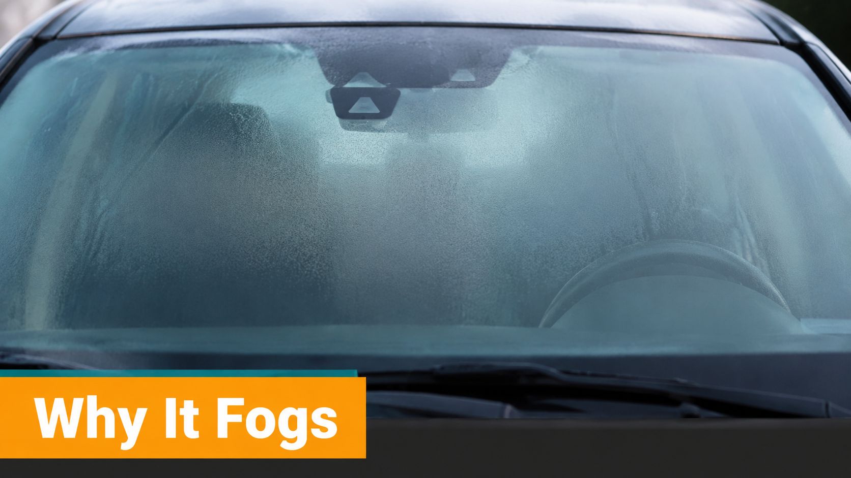 The inside of a car windshield covered in condensation, making it foggy and difficult to see through.