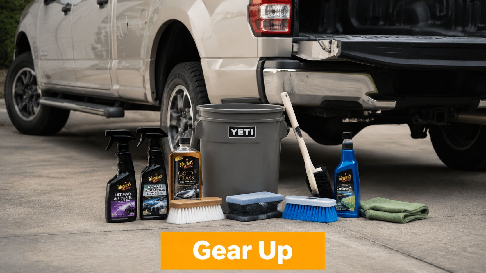 A collection of car cleaning supplies like soap, sponges, and brushes arranged beside a pickup truck.