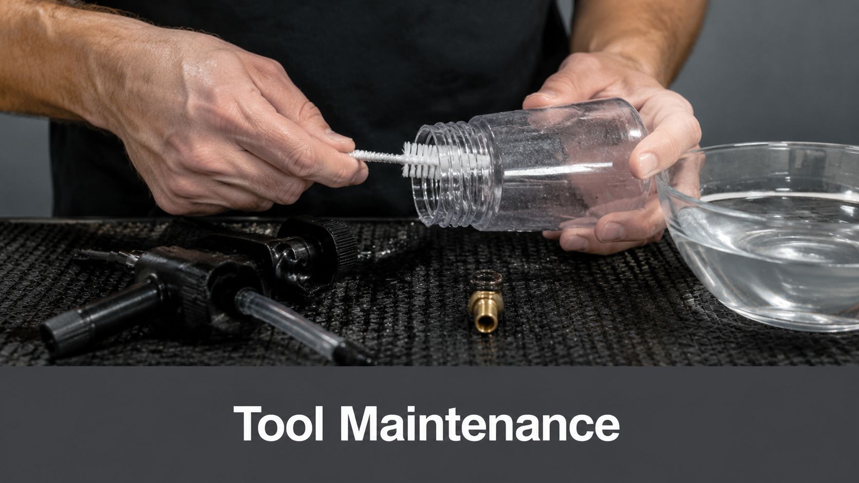 A person cleaning a clear plastic canister with a small white brush for tool maintenance purposes.