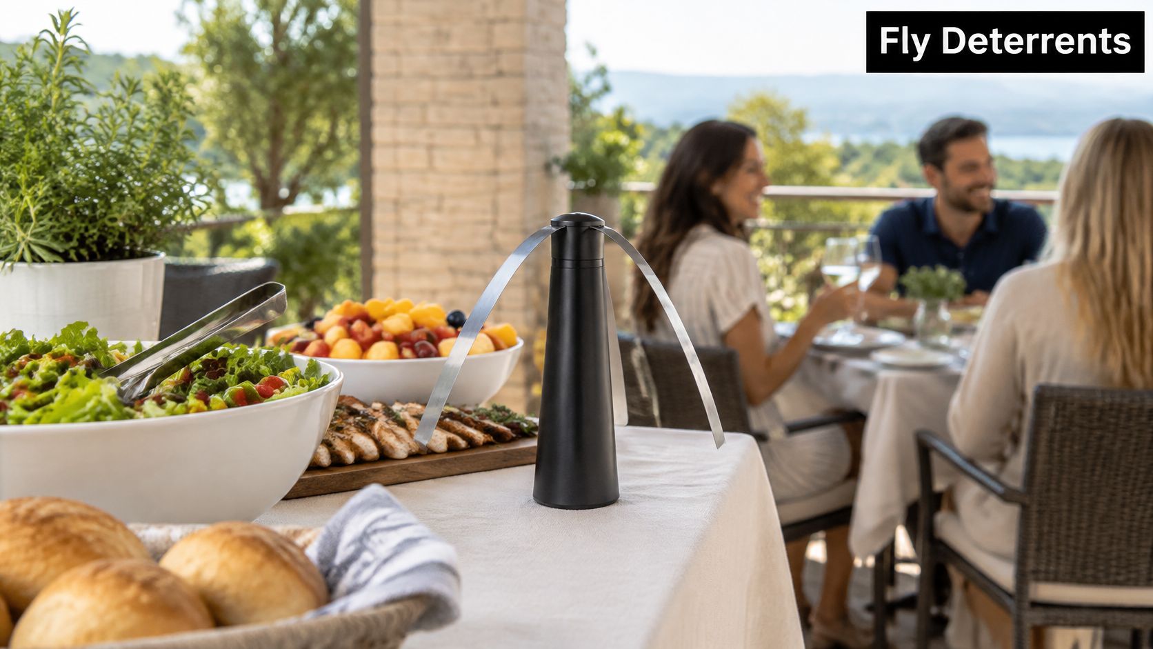 A modern black table-top fly deterrent fan placed on an outdoor dining table during a social gathering.