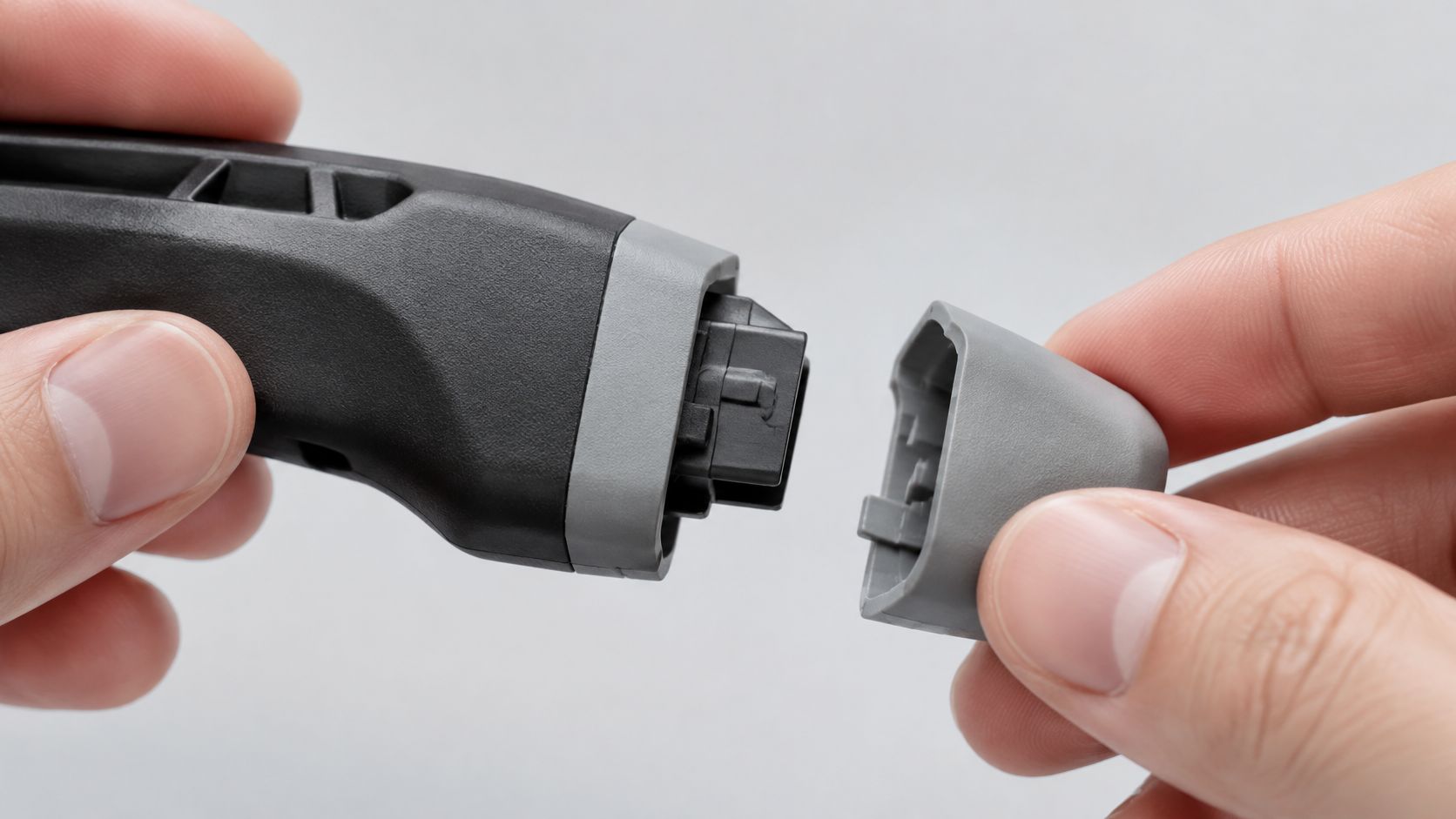 A close-up of a person attaching a grey plastic end cap to a black overmolded handle component.