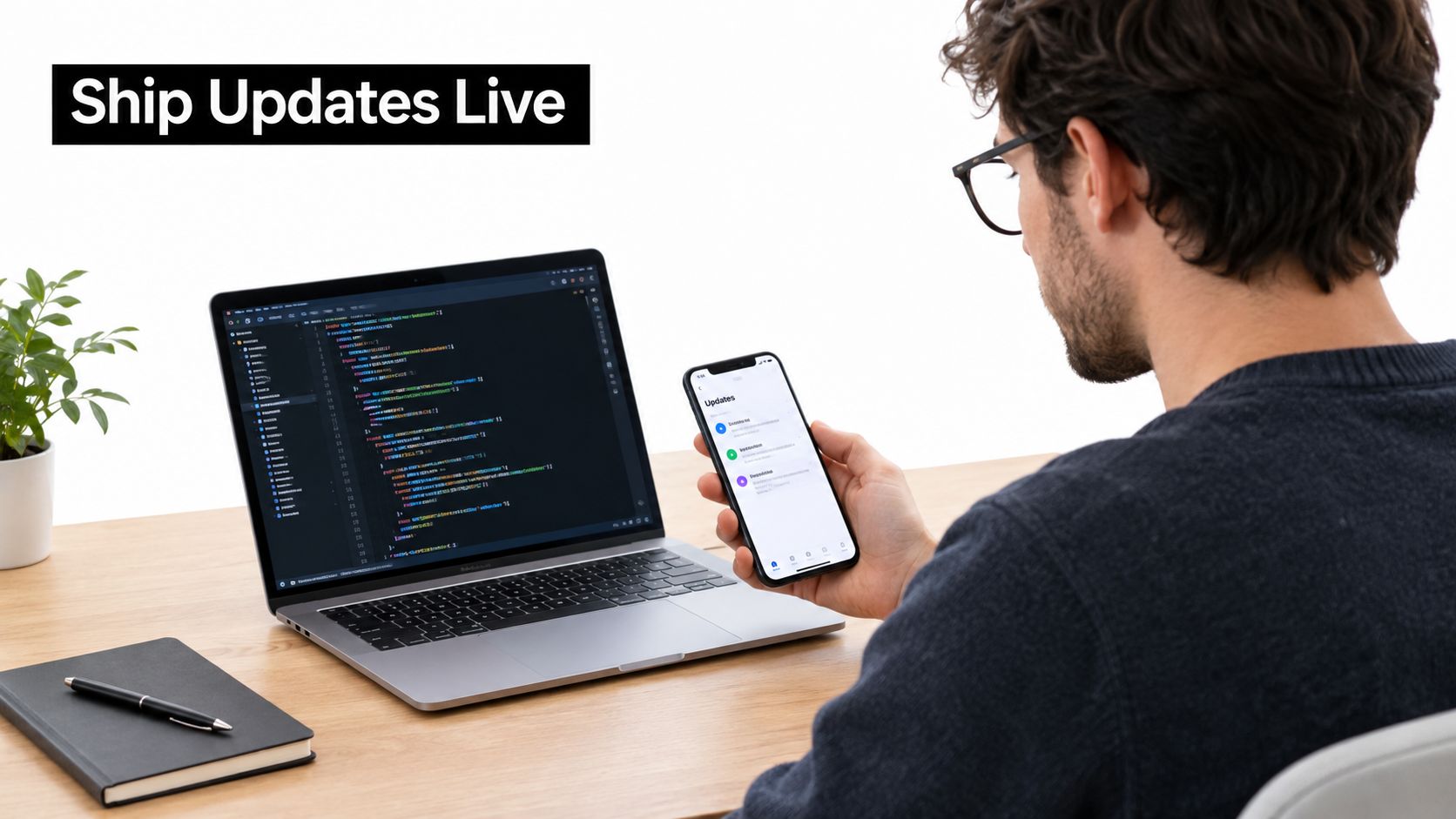 A developer working on code on his laptop while checking mobile application updates on his phone.