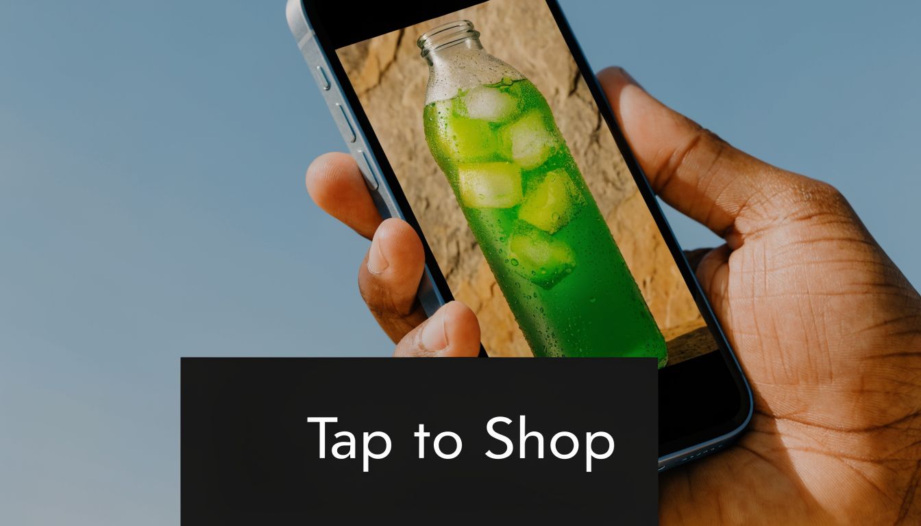 A hand holds a smartphone displaying an image of a green drink with ice in a bottle.