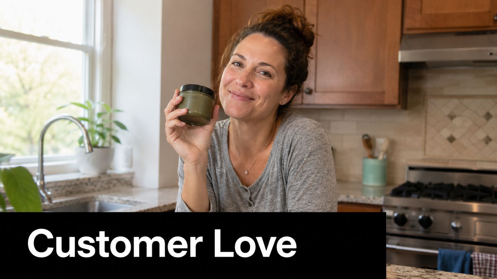 A woman smiling in her kitchen while holding a jar of organic green skincare product.
