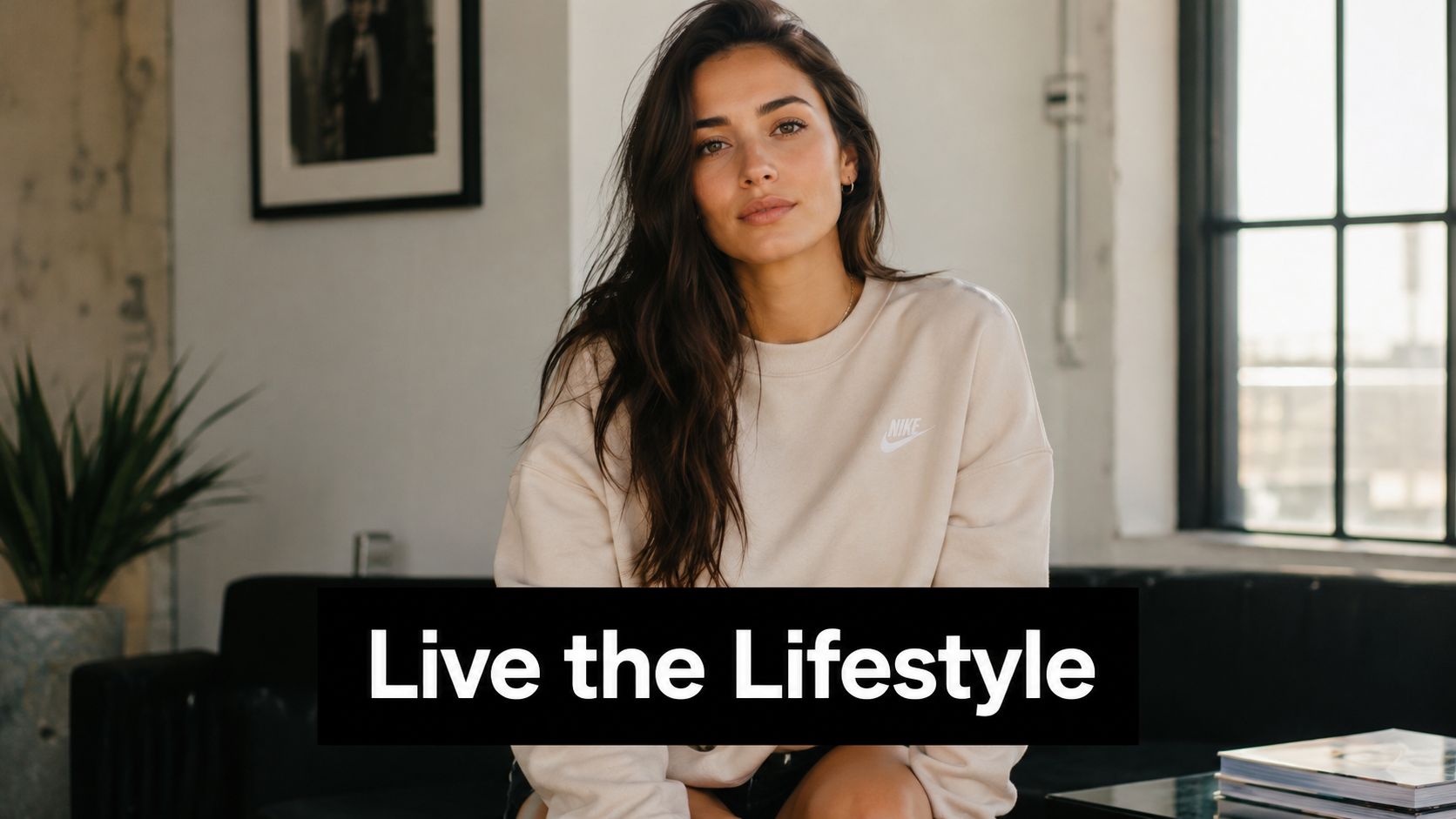 A young woman wearing a beige Nike sweatshirt poses indoors for a stylish lifestyle brand advertisement.