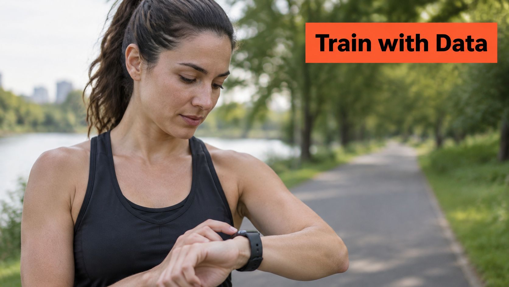 A fit woman in athletic clothing checking her smartwatch while outdoors on a paved park path.