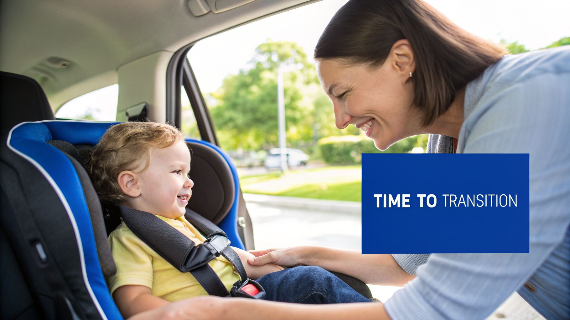 A smiling mother interacts with her happy toddler safely buckled into a blue car seat.