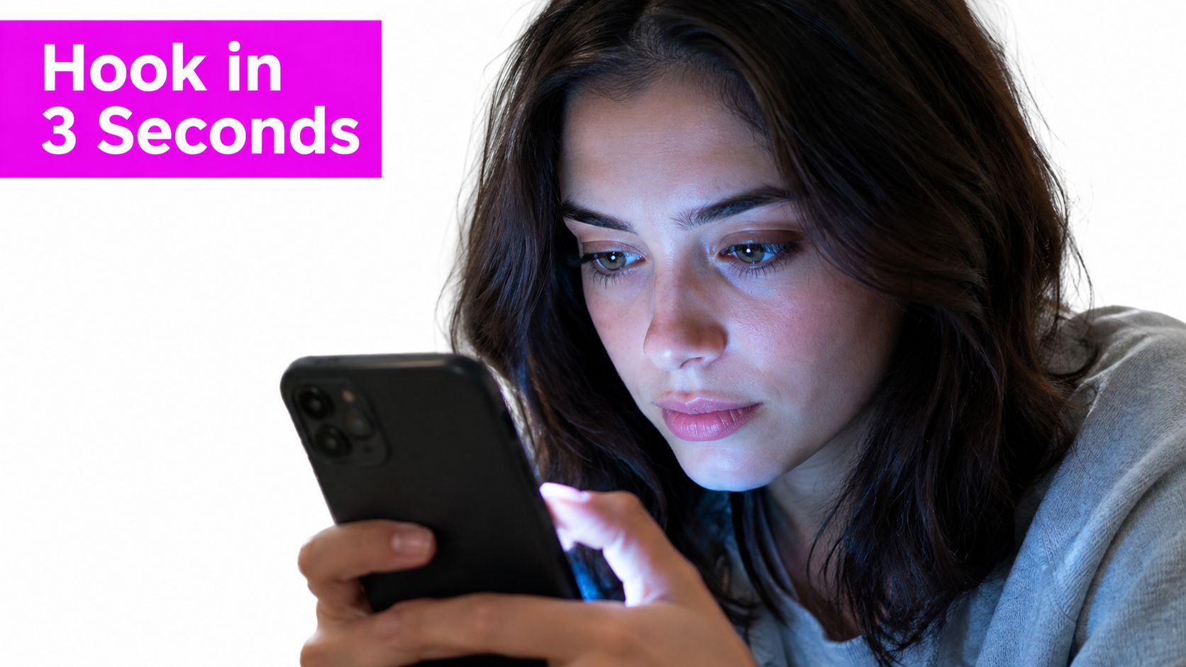 A young woman intently looking at her glowing smartphone screen in a dark environment.