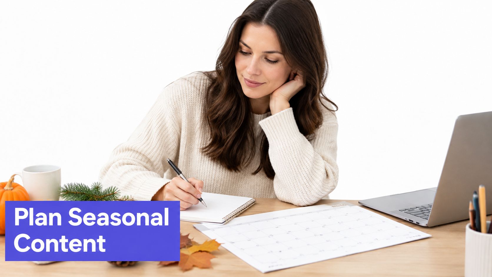 A young woman sits at a desk planning seasonal content on a paper calendar with a laptop.