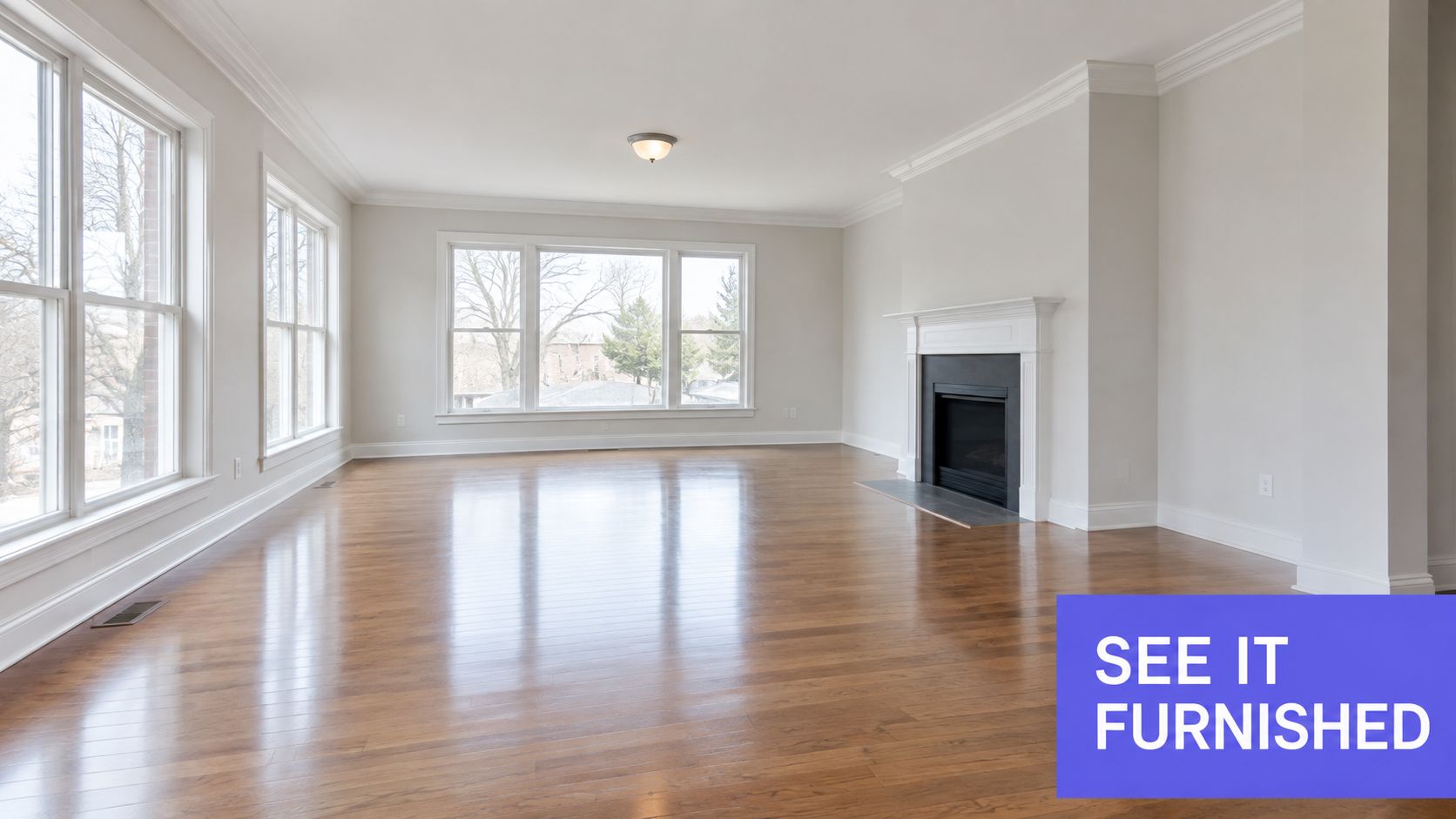 An empty living room featuring hardwood flooring, white walls, and a prominent fireplace with a black insert.