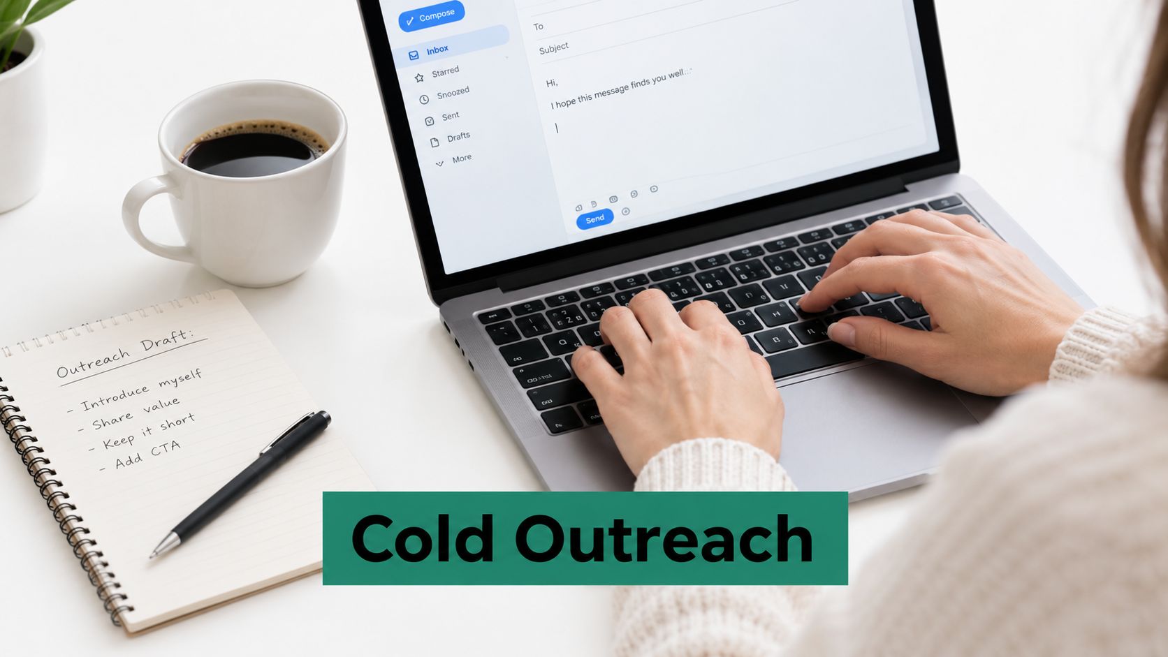 A person writing a cold outreach email on a laptop next to a notebook and coffee.