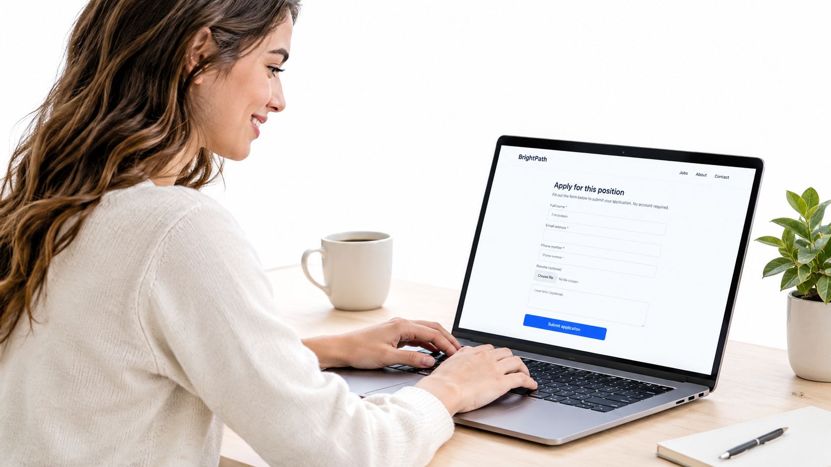 Uma mulher sorridente preenchendo um formulário de candidatura a um emprego online em seu laptop.