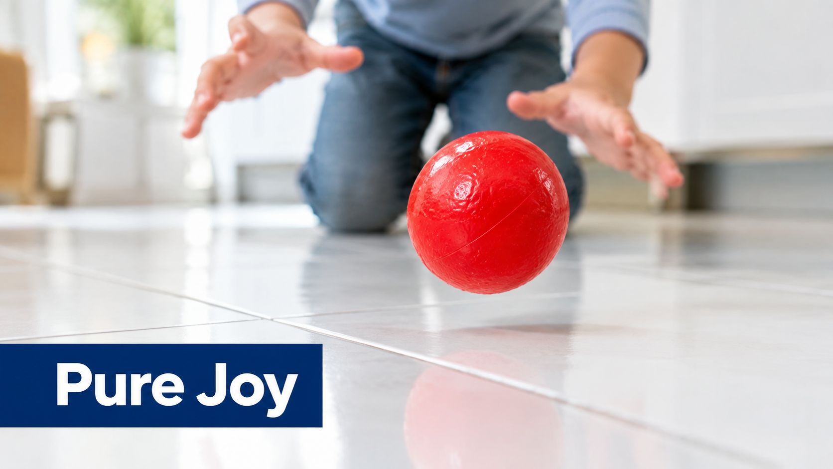 A child playing on a tiled floor while reaching for a bouncing red rubber ball.