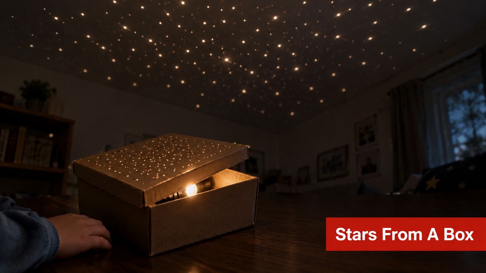 A child's hand next to a cardboard box creating a DIY planetarium projector on the ceiling.