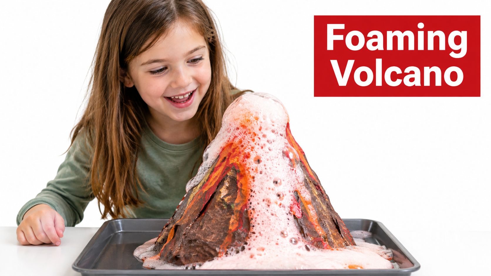 A happy young girl watches a homemade science project with a foaming baking soda volcano erupting.
