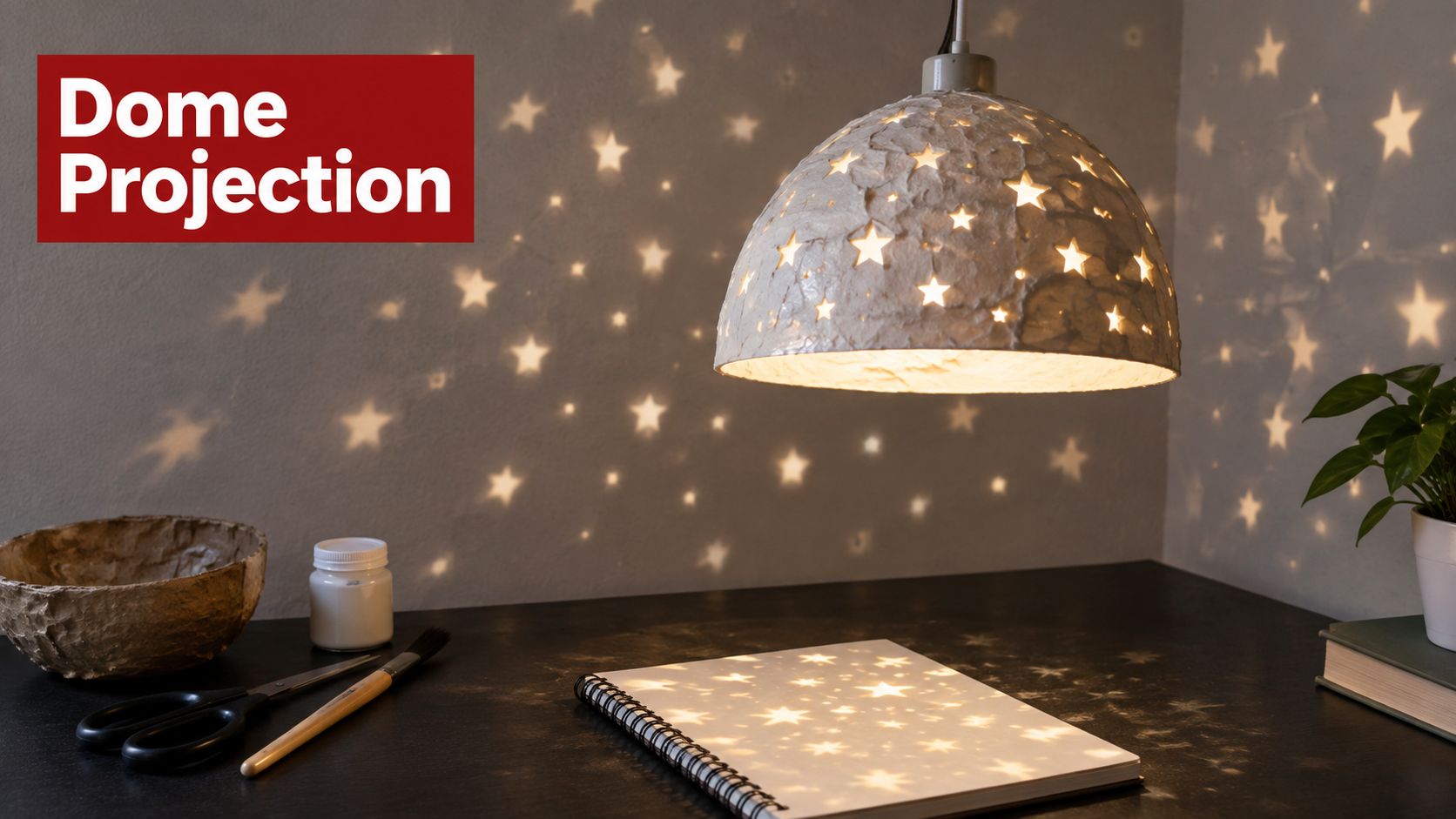 A DIY star dome lamp casting star-shaped light patterns onto a notebook on a dark desk surface.