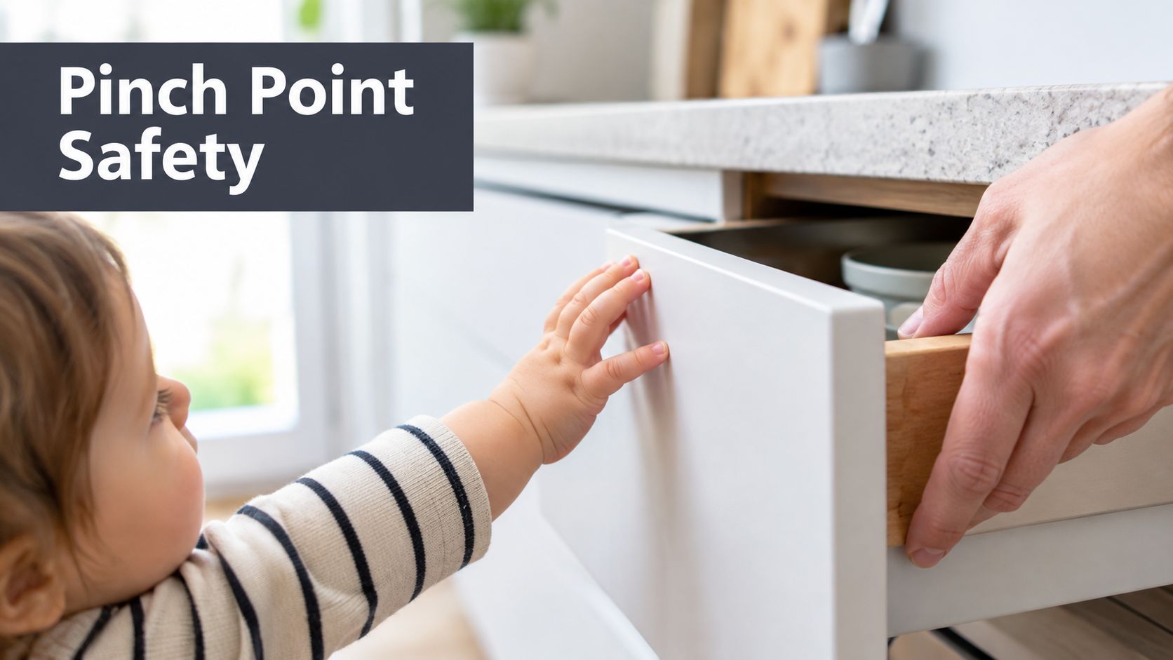 A young toddler reaching toward the opening of a kitchen drawer while an adult pulls it closed.