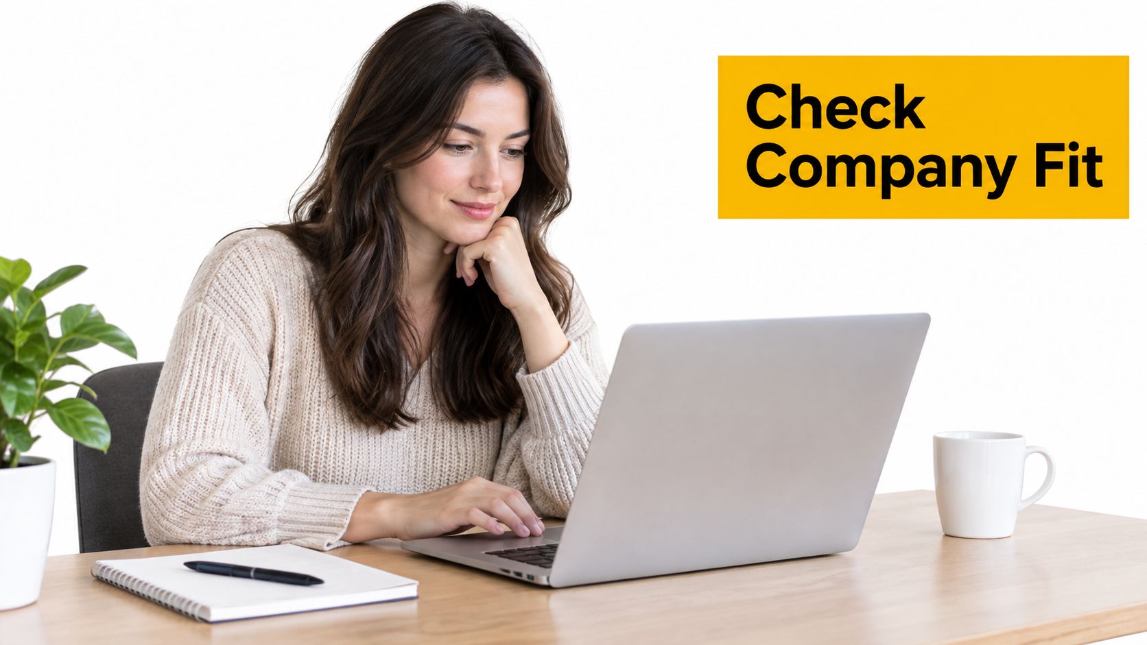 A young woman smiling while working on her laptop to check company fit during a job search.