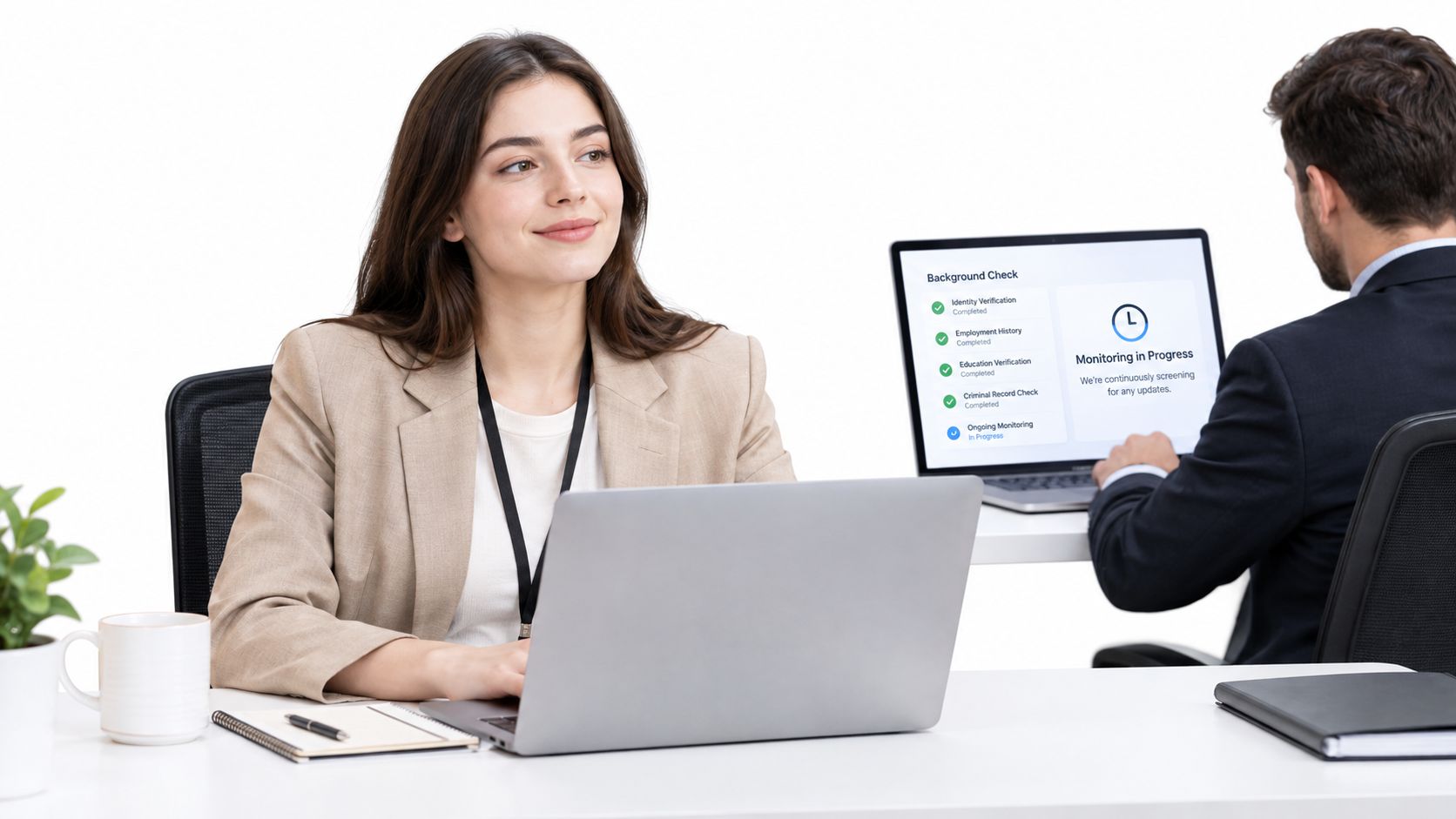 A professional businesswoman looking at her colleague while using a laptop during a background check process.