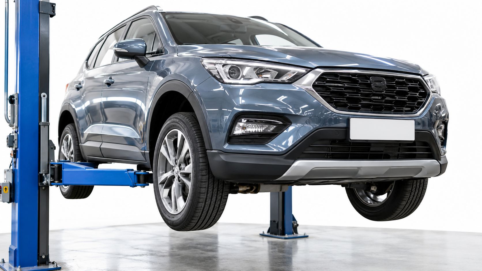 A modern grey compact SUV raised on a blue vehicle lift in a bright workshop.