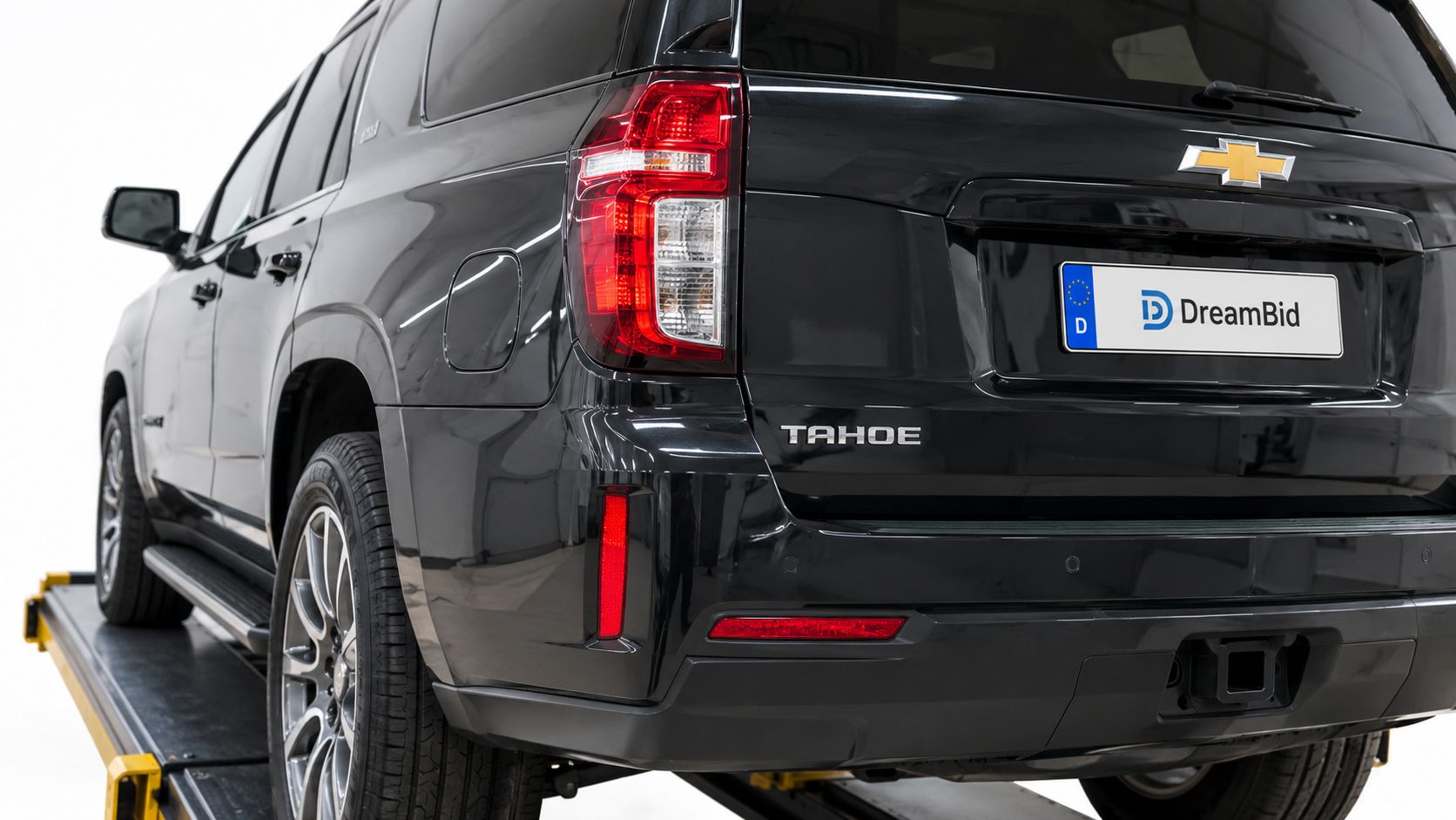 A close-up view of the rear end of a black Chevrolet Tahoe SUV parked on a lift.