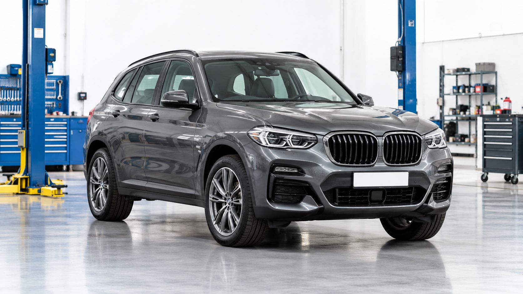 A sleek dark grey BMW midsize SUV parked in a well-lit, professional auto repair garage workshop.