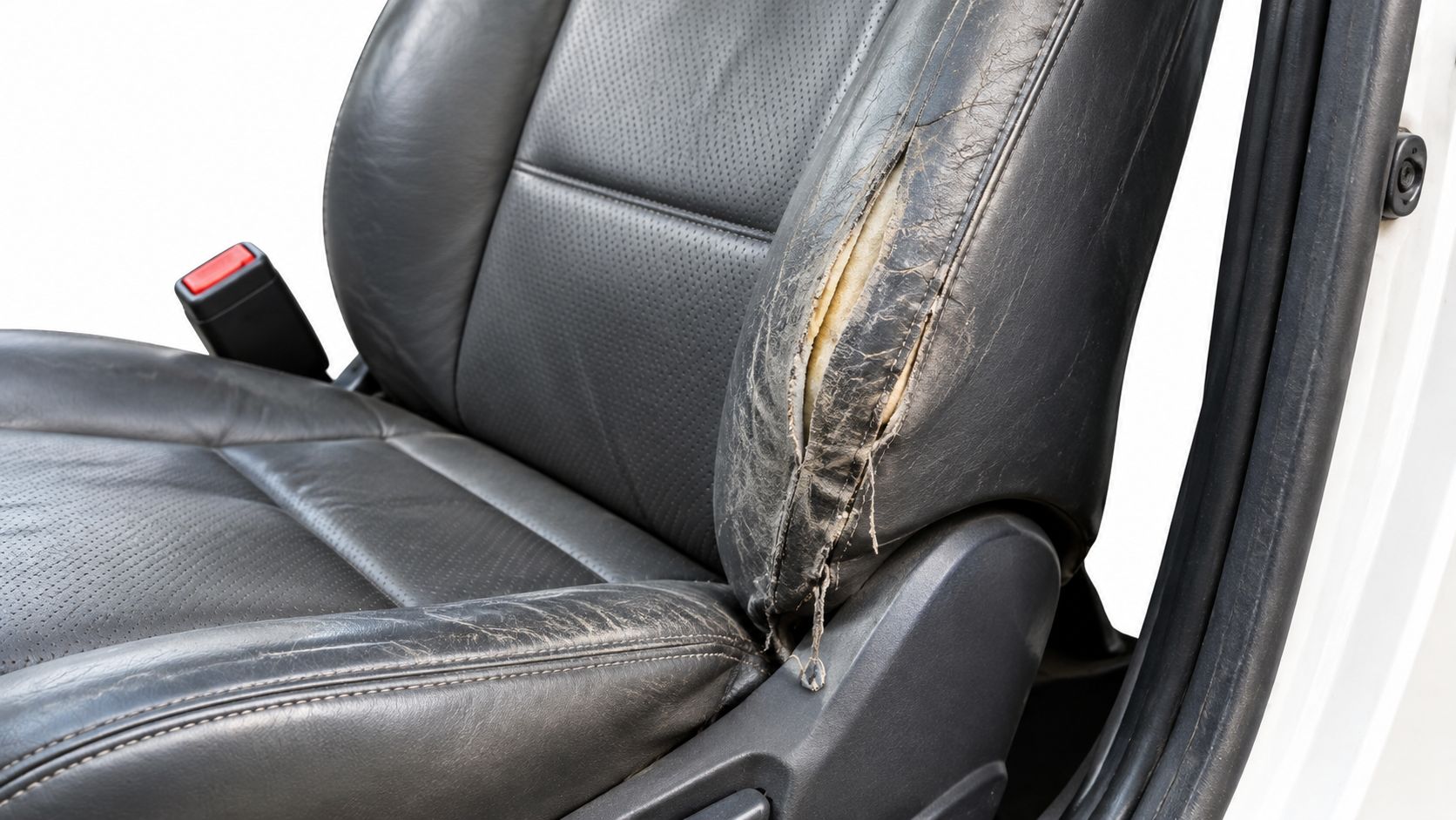 A close-up view of a worn, damaged leather car seat bolster with visible tearing and exposed foam.