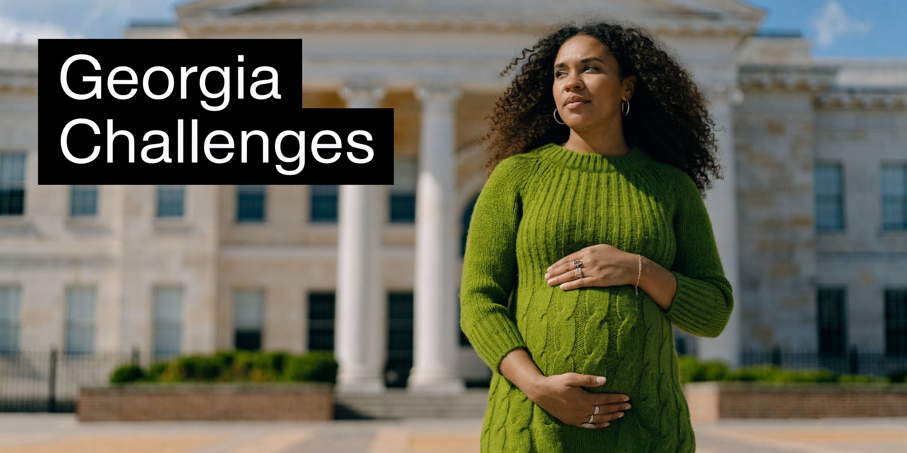 A pregnant woman in a green sweater standing in front of a government building, symbolizing Georgia challenges.