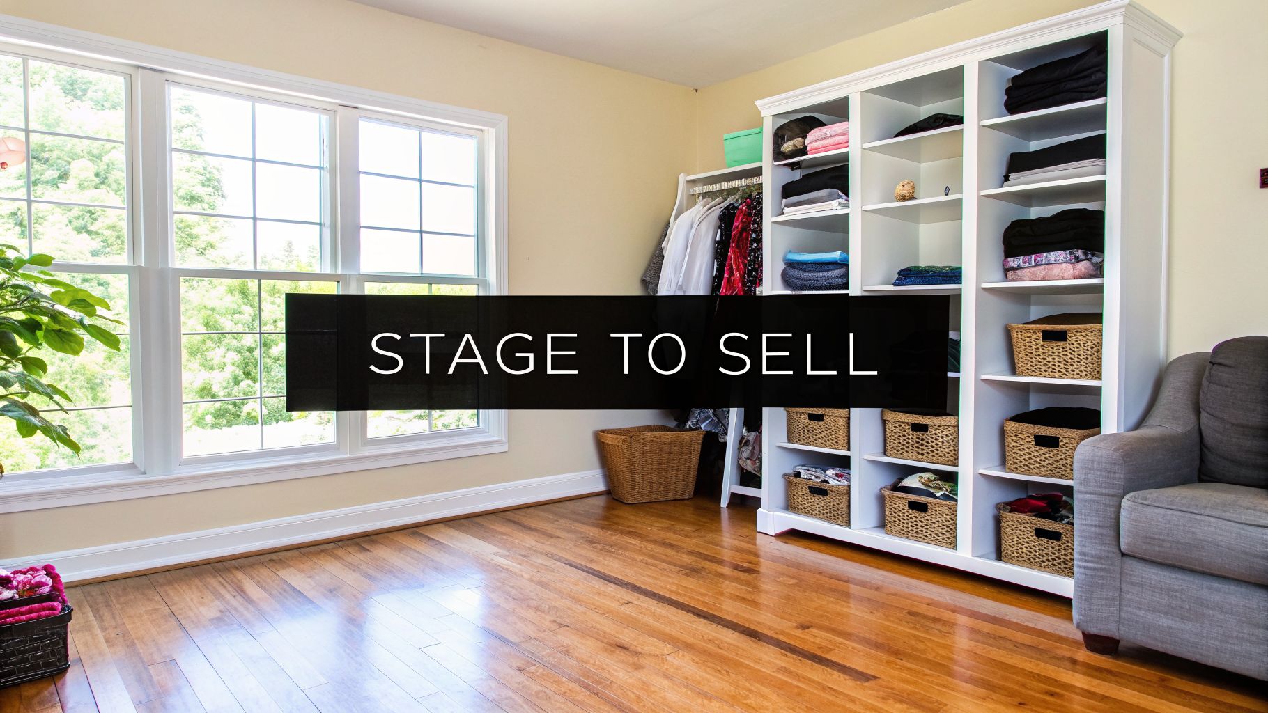 A neatly organized room staged for selling, featuring a white closet, large window, and hardwood floor.