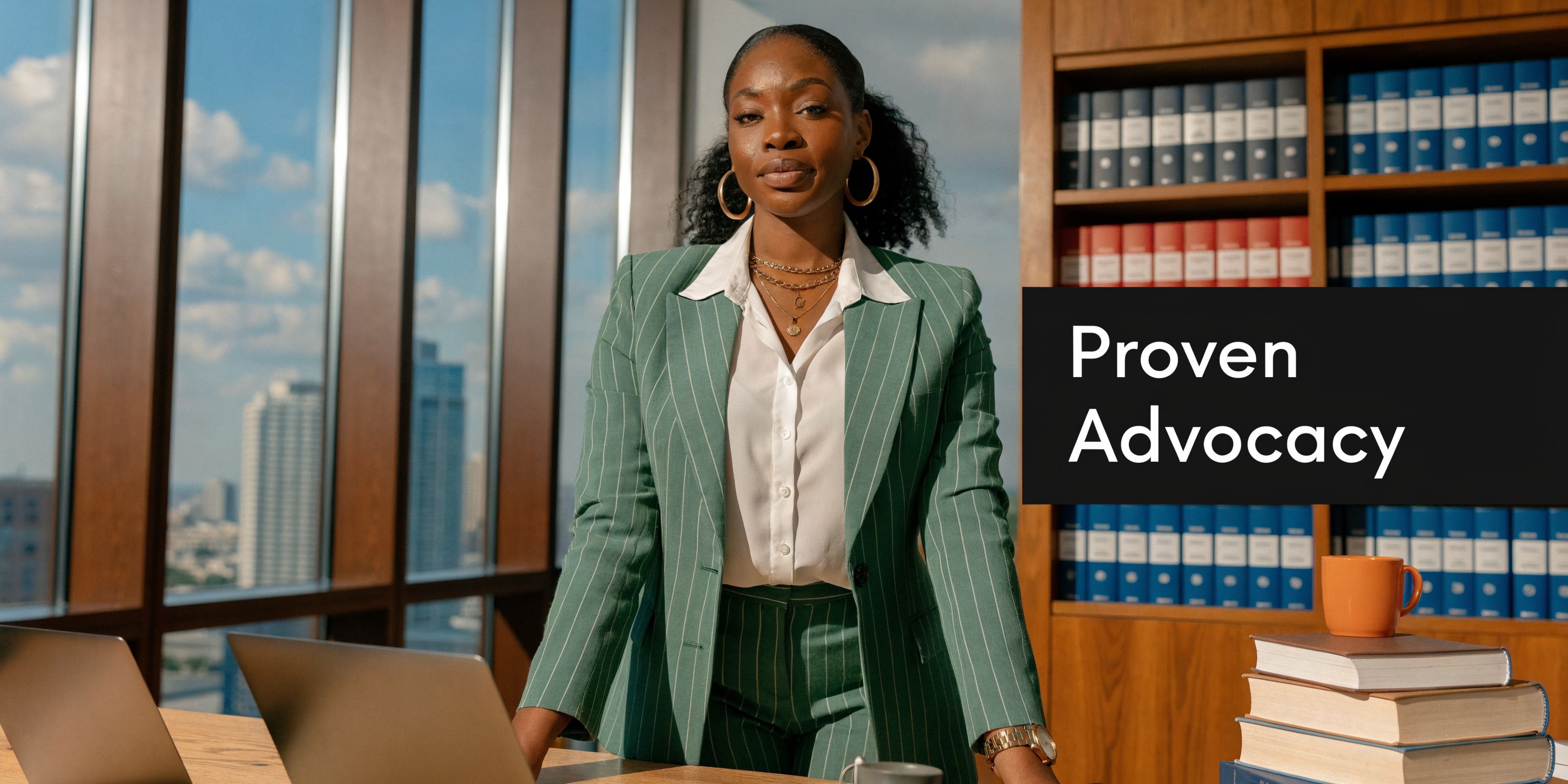 A professional woman in a green suit standing in a modern office with law books and city views.
