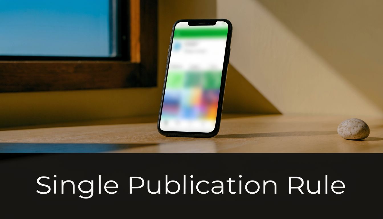 A smartphone on a wooden table with the text Single Publication Rule displayed below the image.